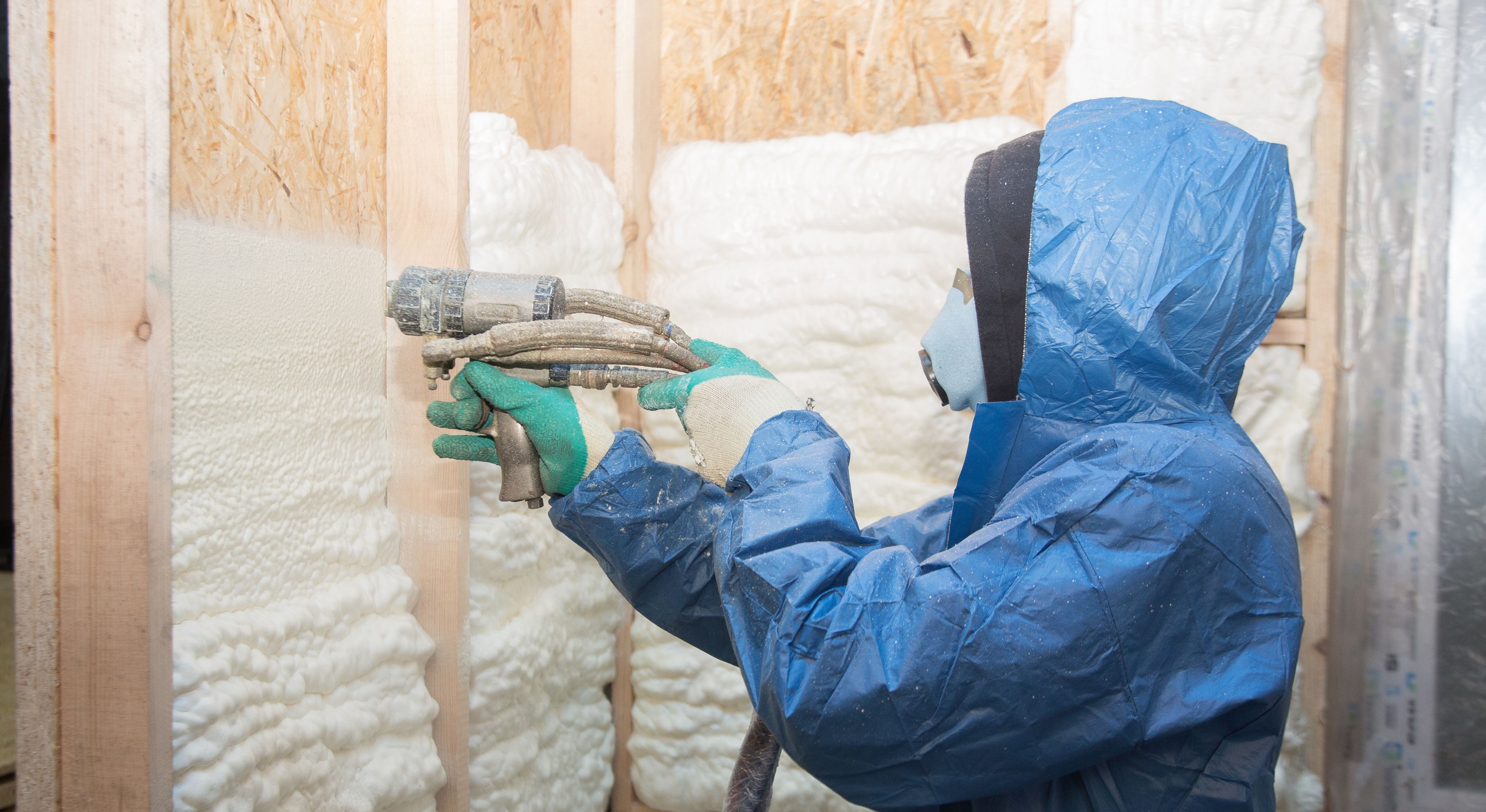 Worker applying for foam to a house.