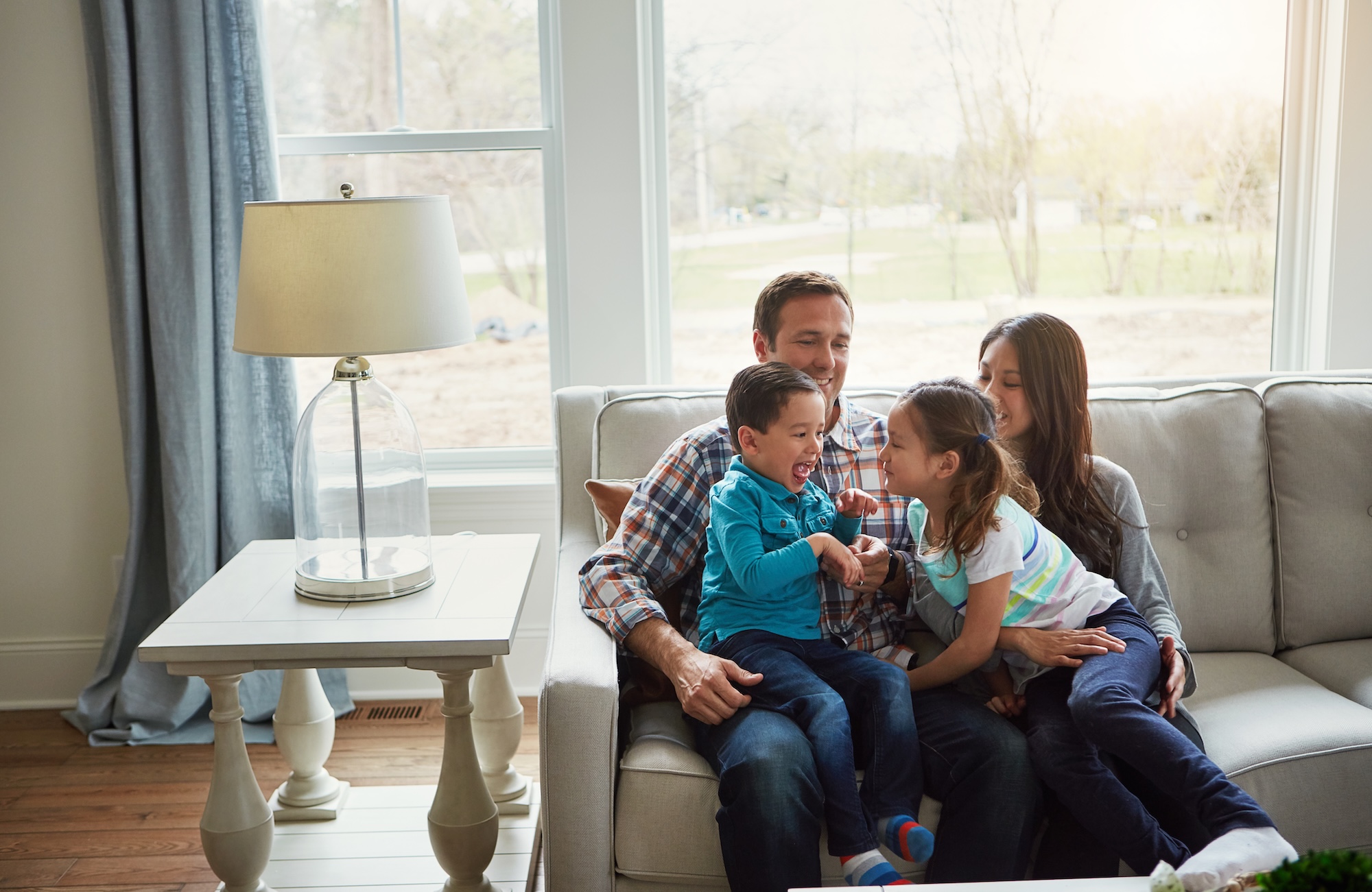 Family of four sitting on tan couch at their home