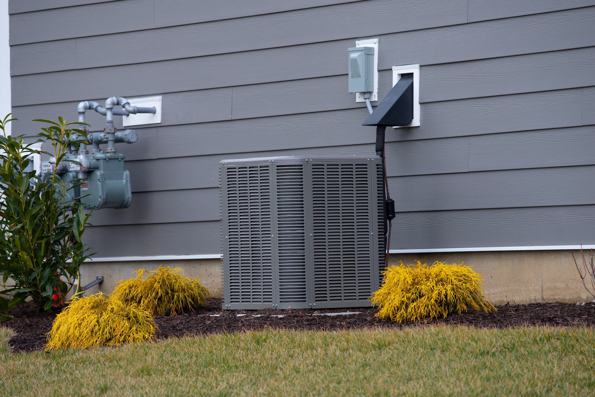 Central air conditioner condenser outside grey-blue residential home