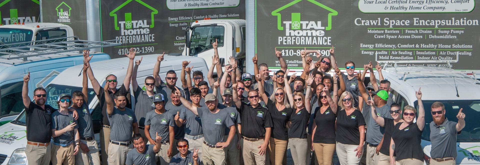 Total home performance team standing in front of branded trucks & vans