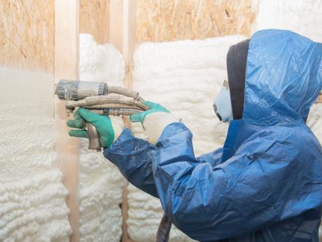 Worker applying for foam to a house.