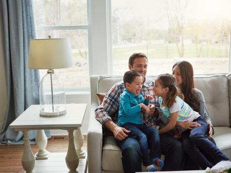 Family of four sitting on tan couch at their home
