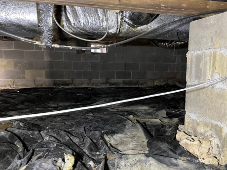 Crawl space vent in background with cement pylon in foreground