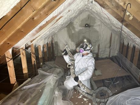 employee in the attic applying spray foam insulation